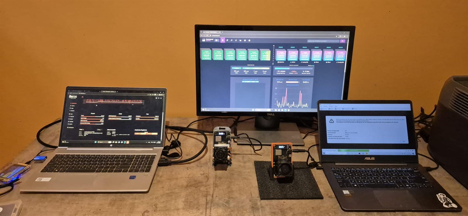 Bitcoin mining dashboards and Bitaxe units on a desk